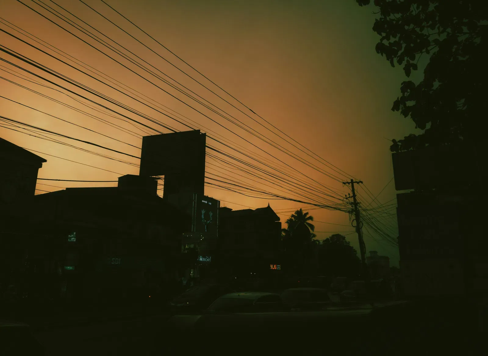 An image of a cityscape with power lines passing through the buildings at dusk.