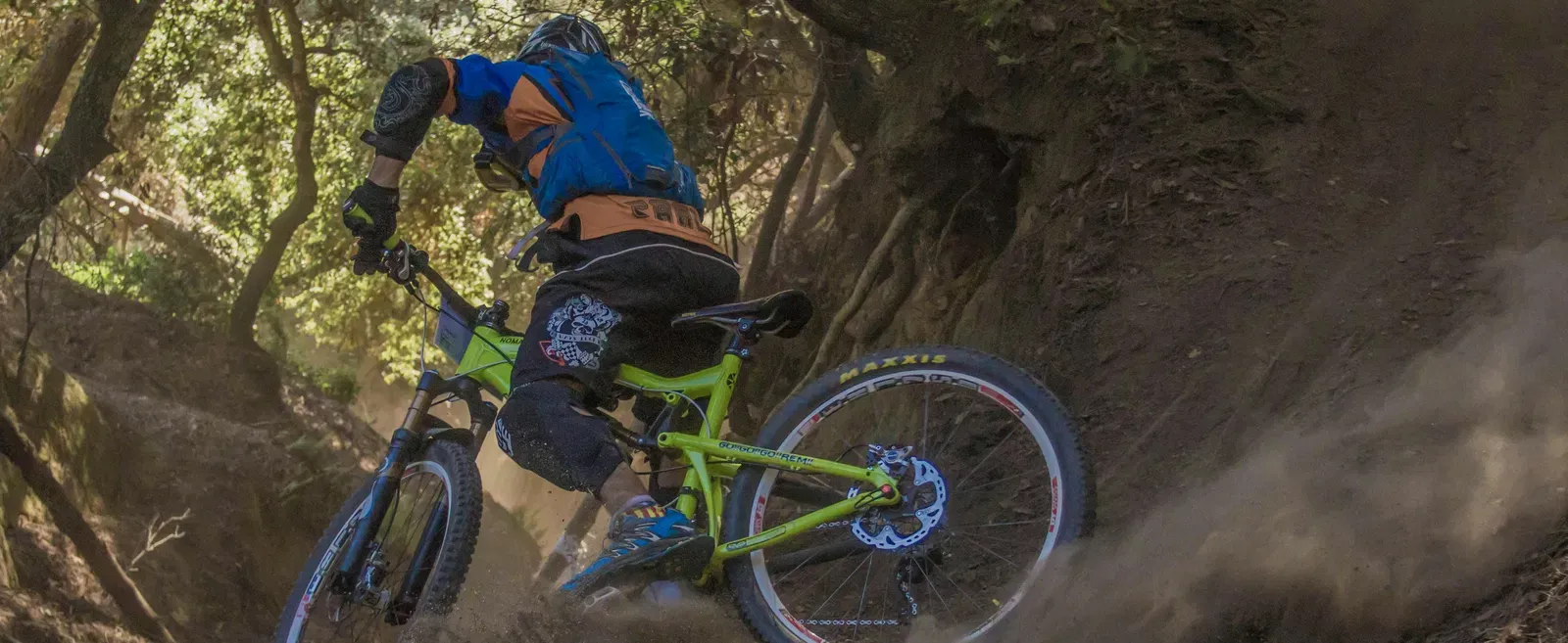 A man cycling on an off road surrounded by a forest.