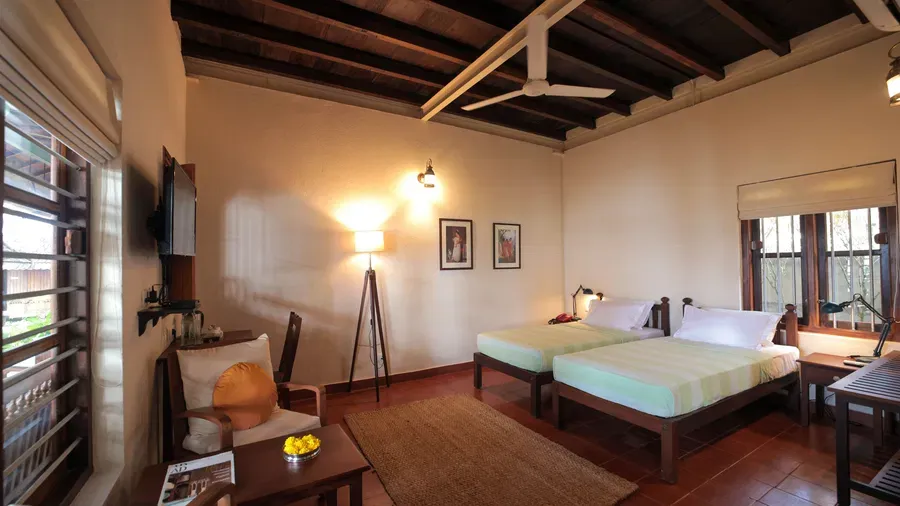 Twin beds placed in front of a desk in Lake Front Verandah Room at Samiira on Ashtamudi Lake. 