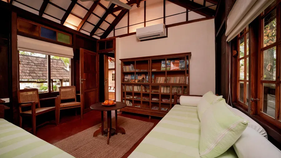 A view of the living room with comfortable seating and a book shelf  at Heritage Cottage at Samiira on Ashtamudi Lake.