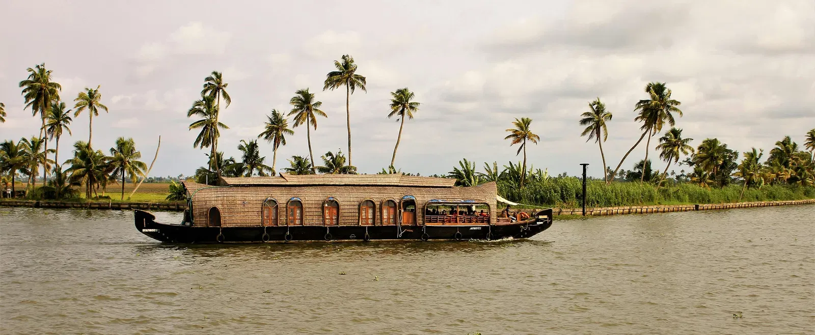 A boat passing by in a lake with trees in the background.
