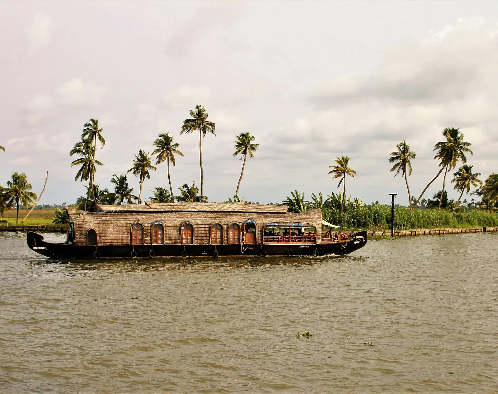 A boat passing by in a lake with trees in the background.